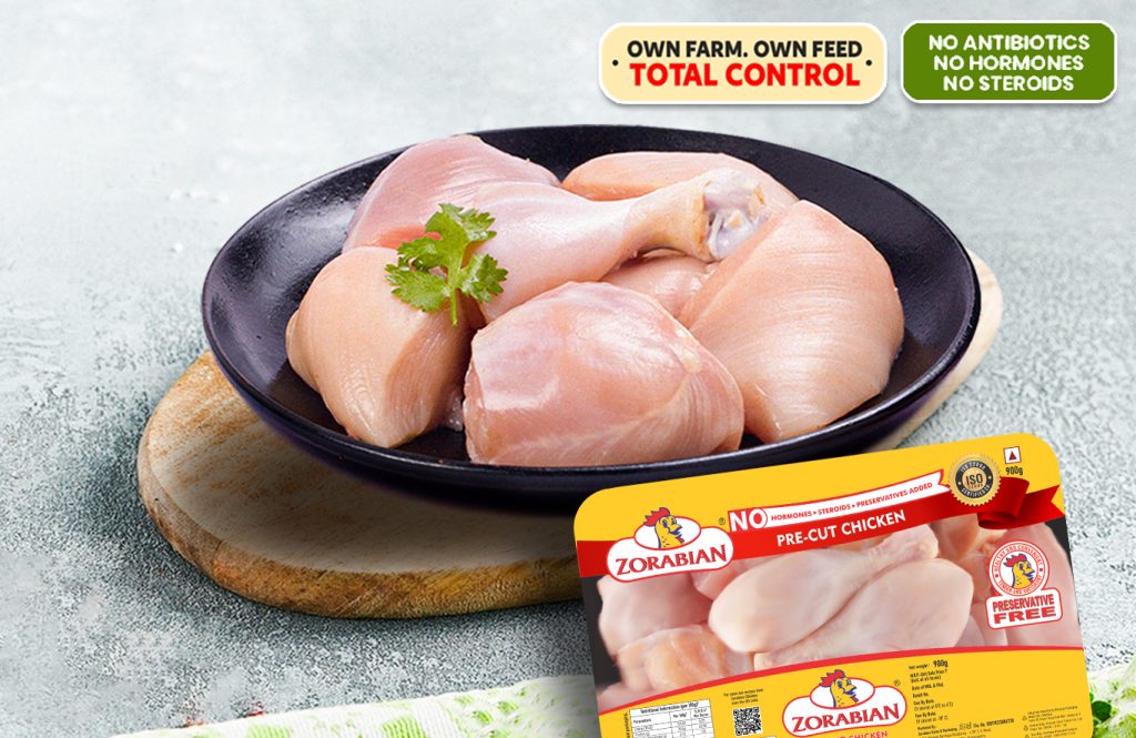 A plate of fresh Zorabian Pre-Cut Chicken pieces on a wooden board, accompanied by a product package highlighting "No Hormones, Steroids, or Preservatives Added" and "Own Farm, Own Feed - Total Control.