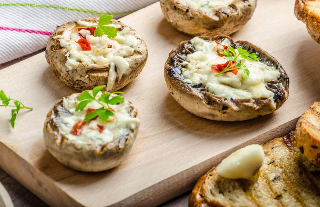 Stuffed mushrooms with chicken mince and cheese on white plate.