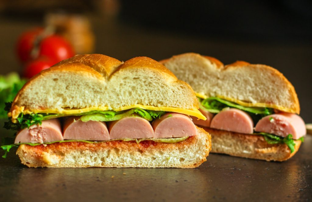 Chicken sausage and egg sandwich with lettuce on white bread.