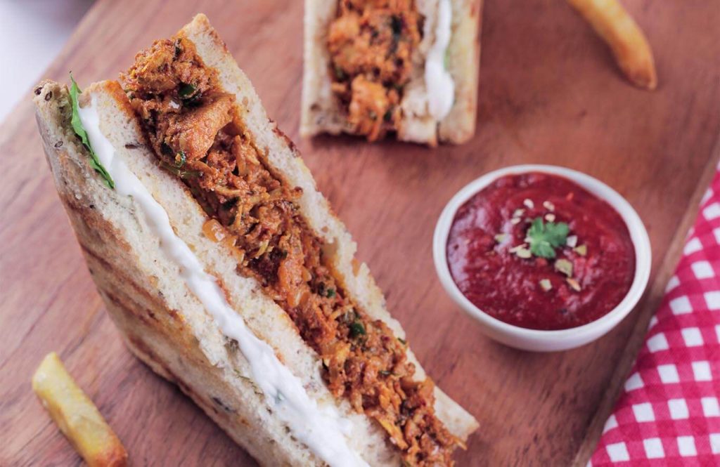 Toasted bread with mashed avocado, tandoori chicken tikka, fried egg, and chili flakes.