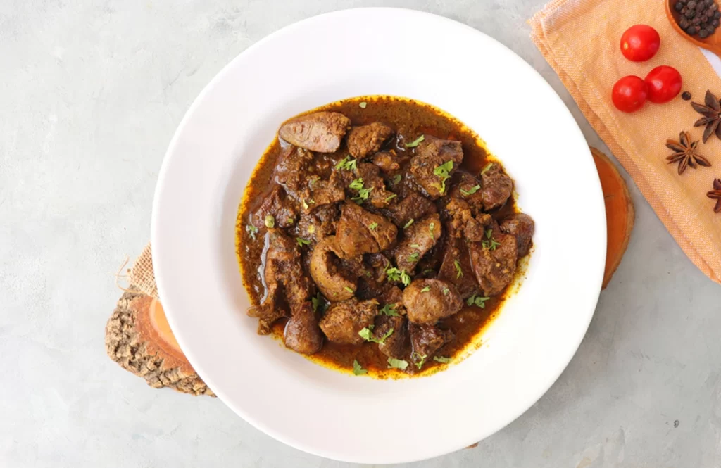Pan-cooked chicken liver in a creamy coconut sauce with onions, garnished with coriander, served in a black bowl.