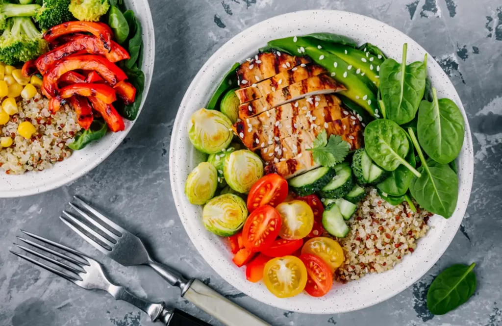 Grilled chicken quinoa bowl with fresh vegetables and greens.