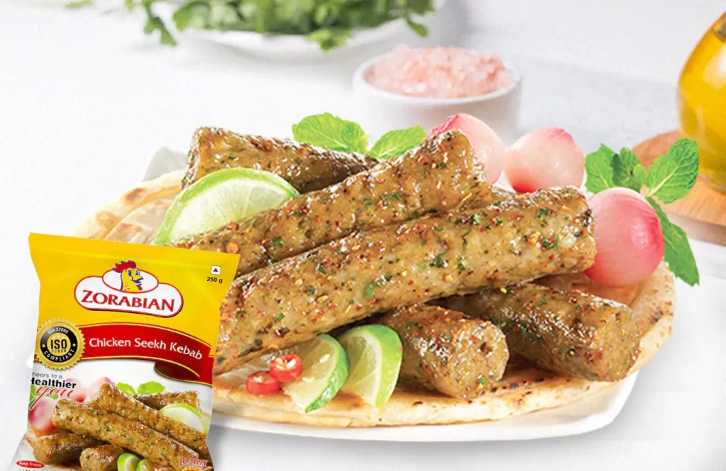 Grilled Zorabian chicken seekh kebabs on skewers with onion slices and chutney, served on a metal tray.