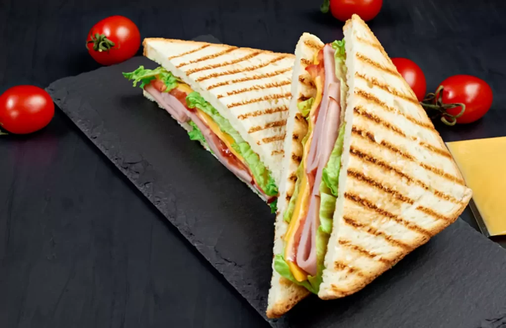 Grilled salami sandwich with lettuce, tomato, and cheese served on toasted bread.