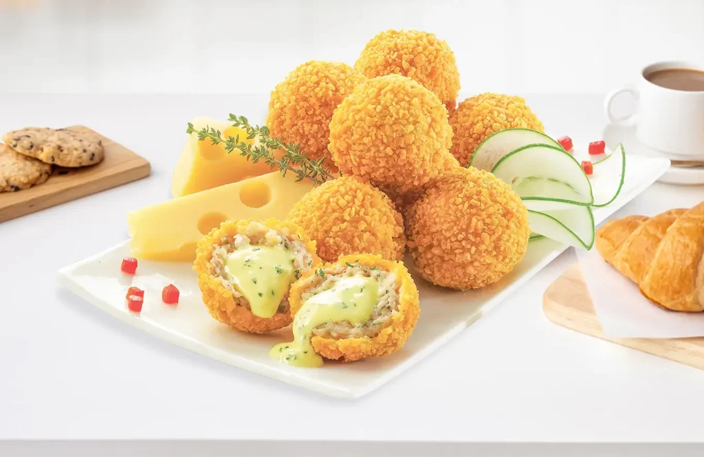 Crispy cheesy chicken balls with creamy melted cheese center on a serving plate.