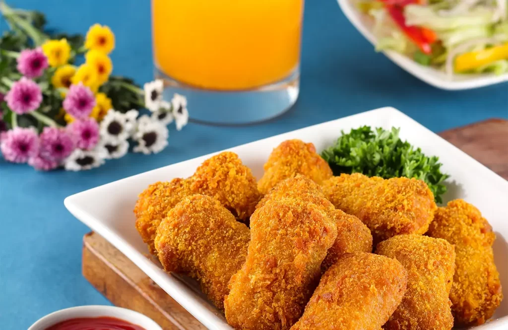Crispy golden chicken nuggets with parsley and ketchup on a blue table.