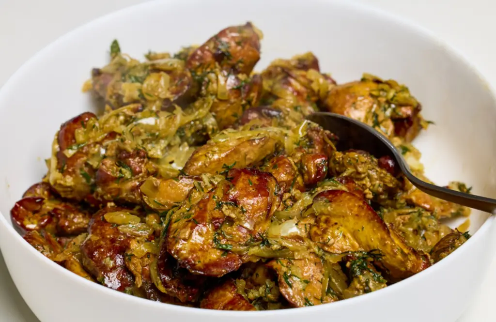 Pepper chicken liver fry with golden onions, curry leaves and crushed black pepper in a white bowl